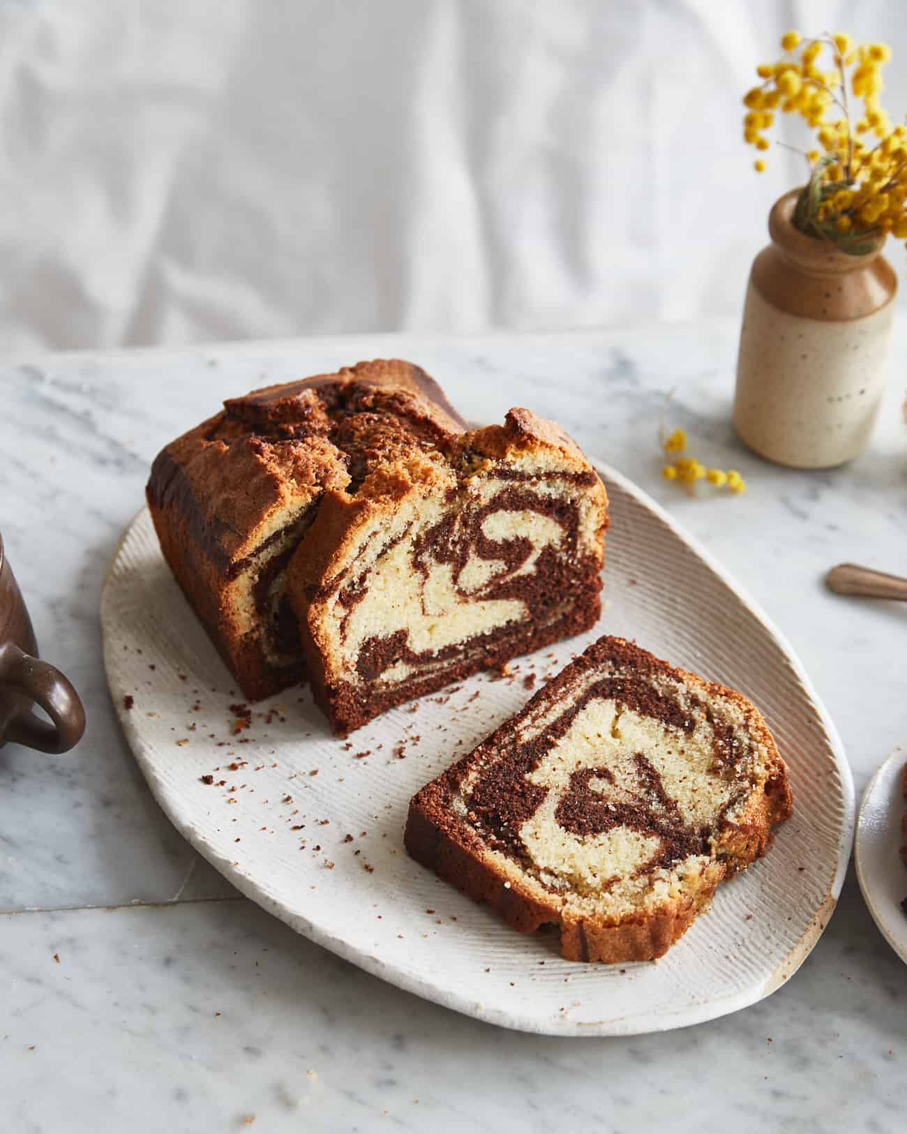 sliced marble cake on a plate with a vase