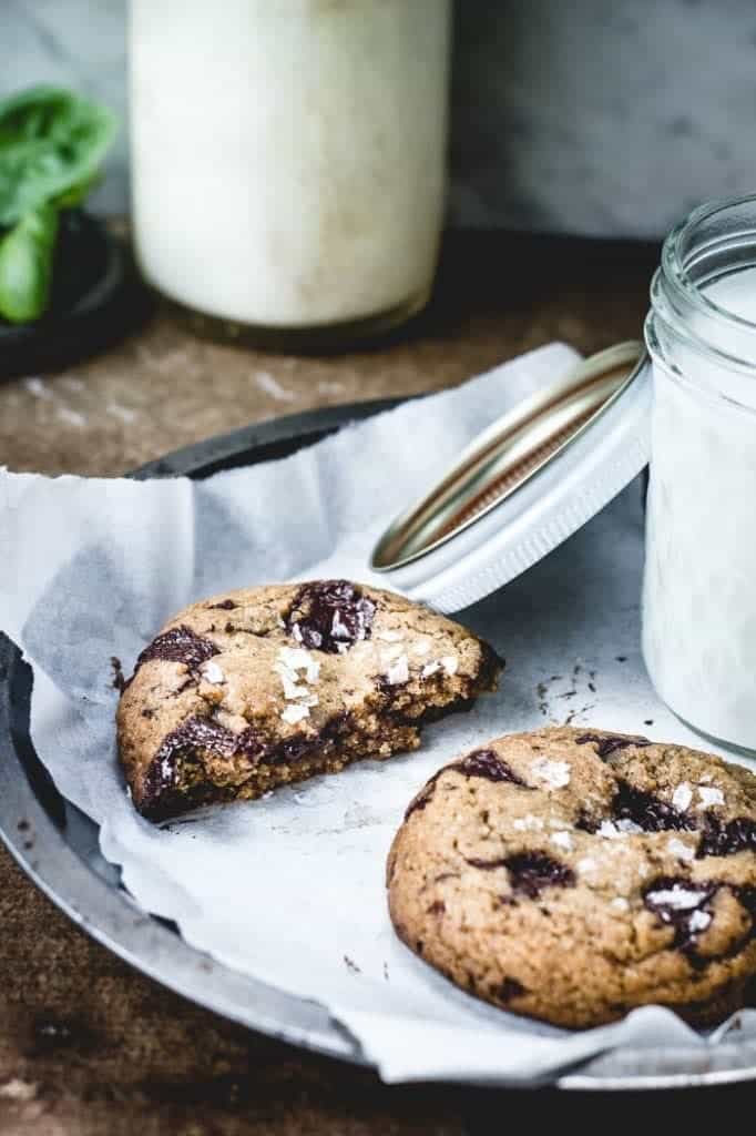 One and a half chocolate chip cookies on a plate with a glass of milk
