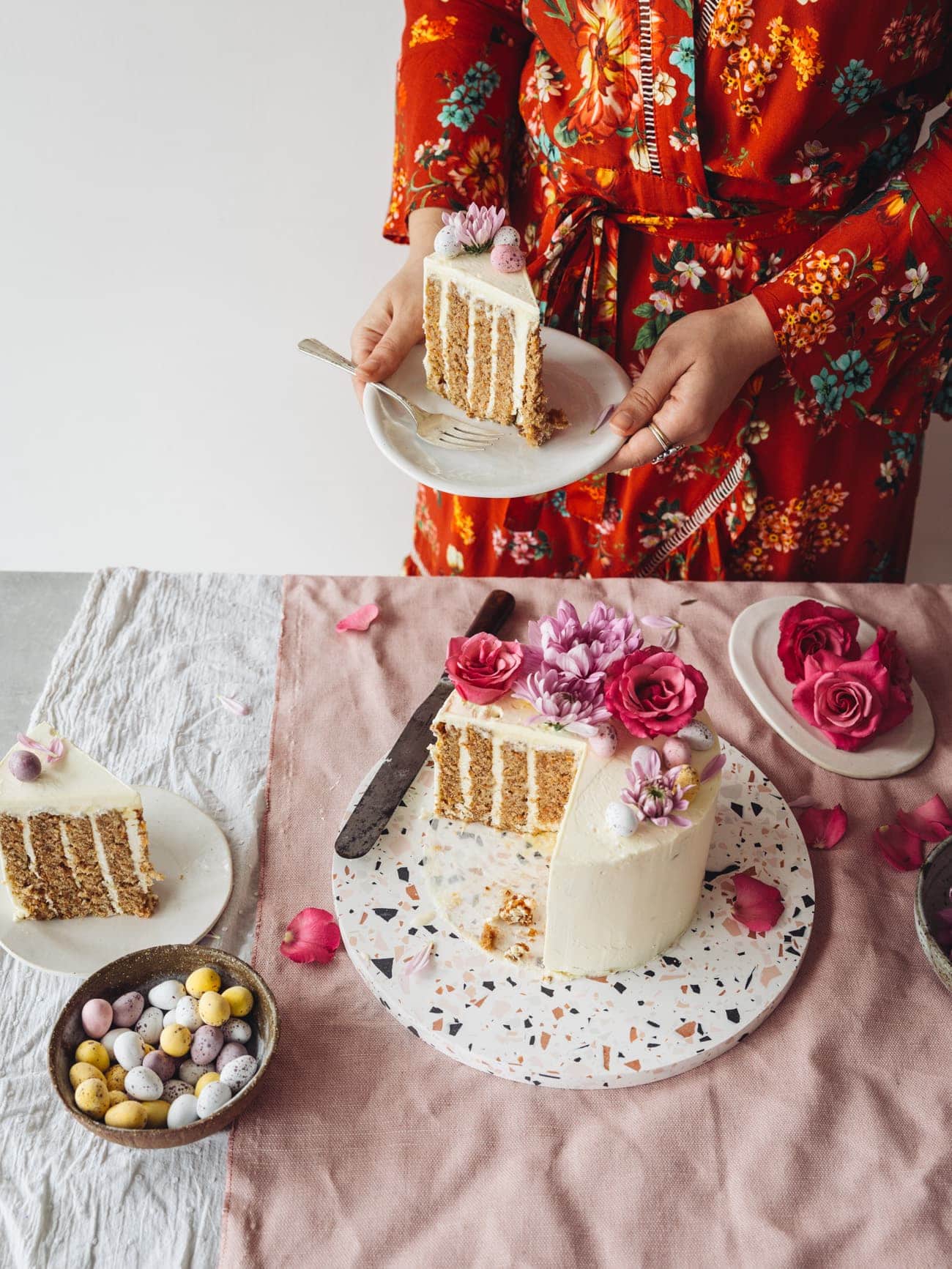 Holding a slice of Vertical Layer Carrot Cake with vanilla Swiss Meringue Buttercream by Izy Hossack