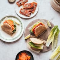 Bao buns filled with crispy gochujang tofu and lettuce with a bamboo steamer