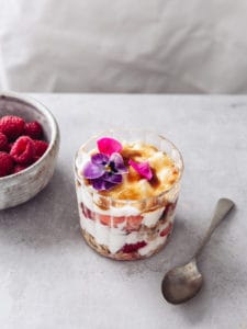 A glass with layers of yoghurt brulee, fruit and granola