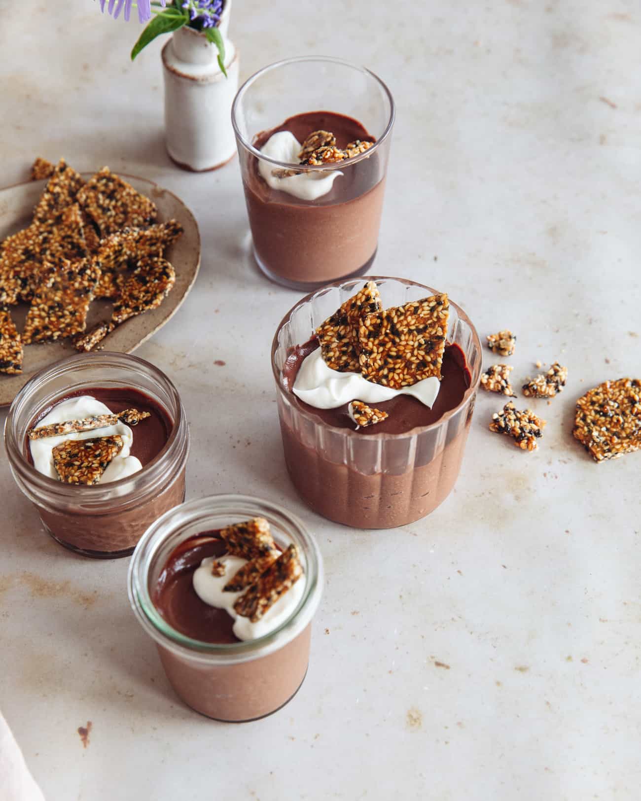 four glasses of chocolate mousse with sesame brittle on top