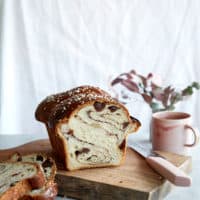 A cinnamon swirled sourdough loaf with a mug of tea on a chopping board