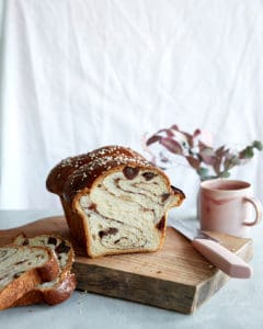 A cinnamon swirled sourdough loaf with a mug of tea on a chopping board