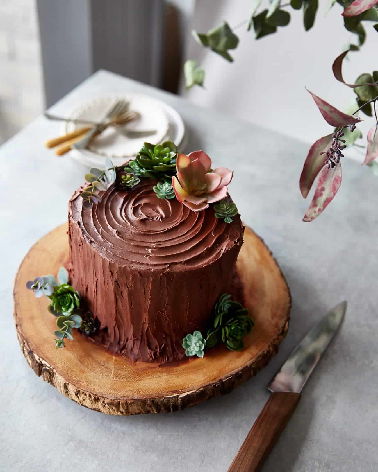 a chocolate tree stump cake on a wooden cake stand