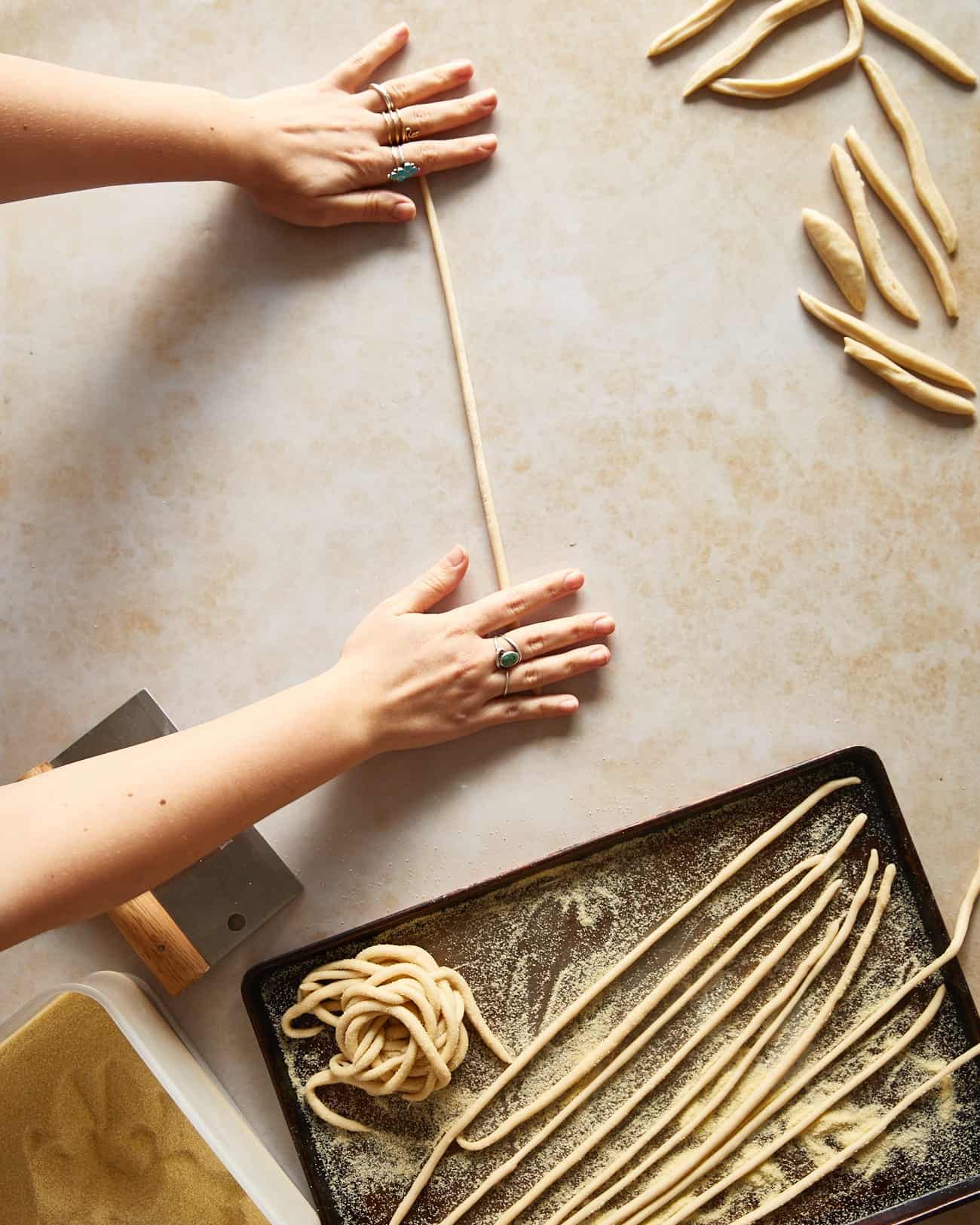 rolling strips of pici dough into worms for cacio e pepe