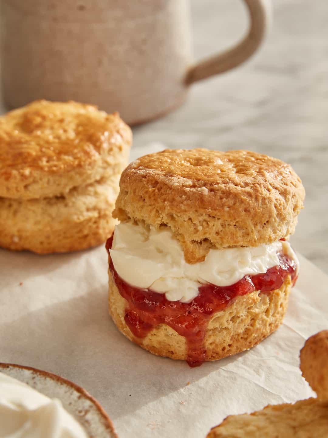 a classic scone, halved and filled with strawberry jam and clotted cream