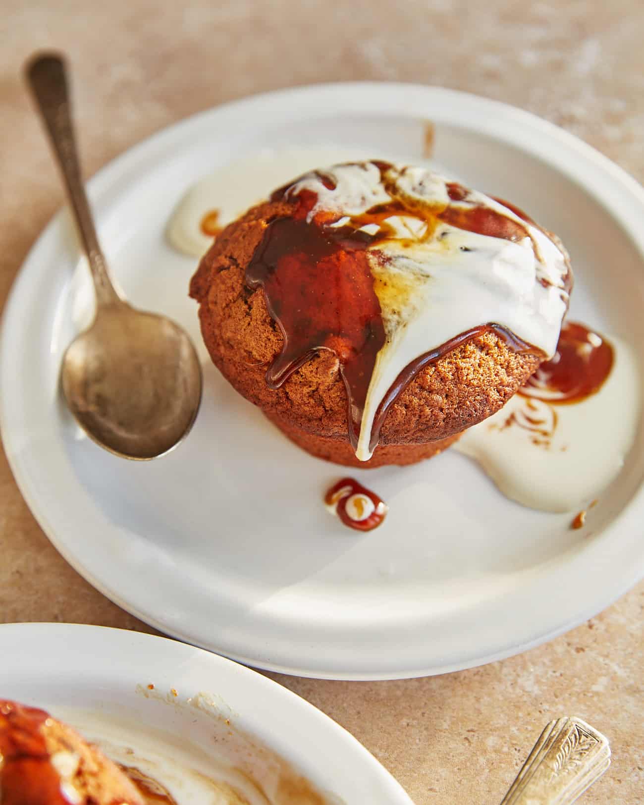 an individual serving of vegan sticky toffee pudding drizzled with toffee sauce and soy cream