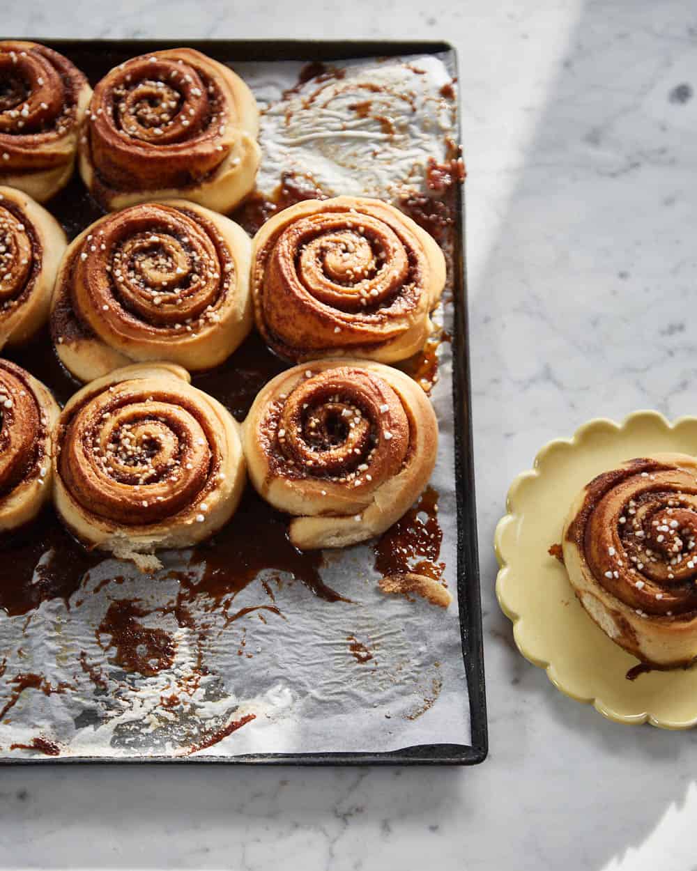 vegan cinnamon rolls on a tray with one on a plate next to it