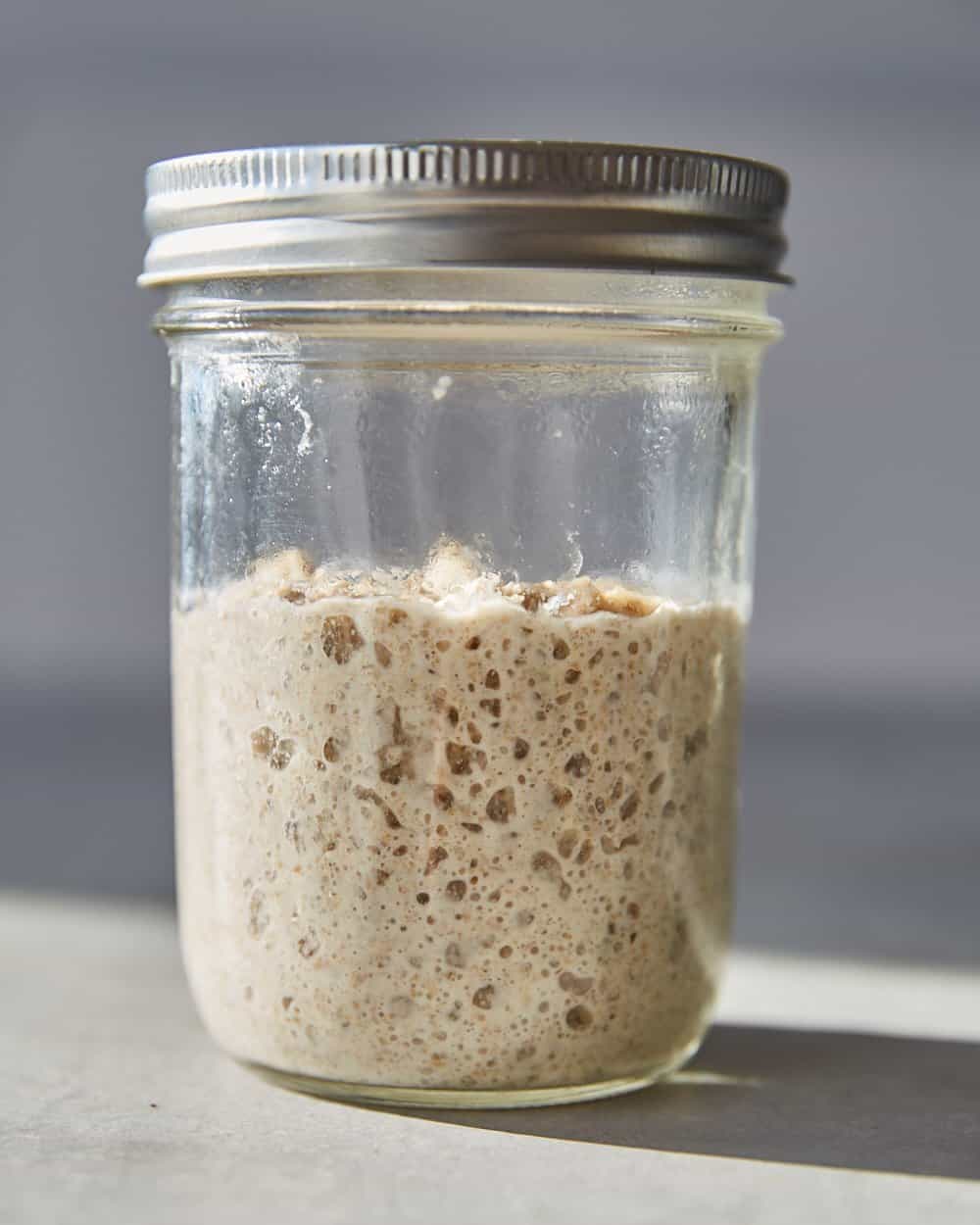 a risen, bubbly stiff sourdough starter in a jar