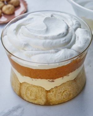 adding whipped cream to jubilee pudding trifle