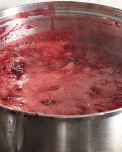 damson jam cooking with foam on top