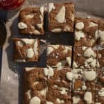 white chocolate chunk biscoff blondies sliced with a jar of biscoff spread behind